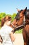 Young redhead teenage girl kissing her favorite chestnut horse.