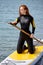 young redhead wet woman in wetsuit swimsuit energetically balancing on subsurfing board