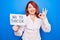 Young redhead woman asking for stop depression holding paper with not to suicide message doing ok sign with fingers, smiling