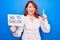 Young redhead woman asking for stop depression holding paper with not to suicide message smiling with an idea or question pointing