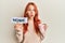 Young redhead woman drinking a cup of coffee holding home text afraid and shocked with surprise and amazed expression, fear and