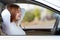 Young redhead woman driver fastened by seatbelt resting in a car smiling happily