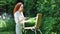 Young redhead woman with an easel in the forest