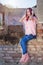 Young Redhead Woman Enjoying Music on Headset on Ruins Wall at Sunset - Vertical Image