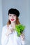 Young redhead woman in hat holding herbs of oregano