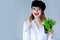 Young redhead woman in hat holding herbs of oregano