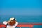 Young redhead woman in hat on pier looks out into ocean