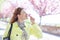 Young redhead woman smelling cherry blossom at park during springtime eyes closed