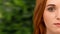 Young redhead woman touching her face, green background