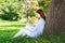 Young redhead woman using smartphone under tree