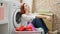 Young redhead woman washing clothes stressed at laundry room