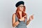 Young redhead woman wearing fashion french look with beret pointing aside worried and nervous with both hands, concerned and