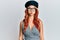 Young redhead woman wearing fashion french look with beret puffing cheeks with funny face