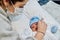 Young redheaded mother with preventive health mask and lgtbiq+ bracelet, next to her newborn baby playing and laughing together on