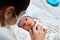 Young redheaded mother with preventive health mask and lgtbiq+ bracelet, next to her newborn baby playing and laughing together on