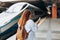 Young redhhead woman waiting train on station platform with backpack and using smart phone. Railroad transport concept