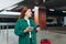 Young refugee redhhead woman crying and waiting train on station platform, she lost and using smart phone. Railroad