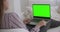 Young relaxed woman is using laptop with green screen for chroma key technology for chatting in internet, calling by