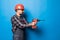 Young repairman with drill perforator isolated on blue background