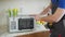 Young repairman fixing and repairing microwave oven by screwdriver in kitchen