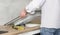 A young repairman installs a black induction hob in a modern white Scandinavian style kitchen