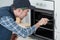young repairman in overall installing brand new oven in kitchen