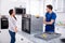 Young Repairman Repairing Oven On Kitchen Worktop