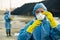 Young researcher in protective workwear looking at sample of toxic soil in flask