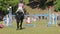 A young rider gallops on a horse, jumping over barriers in equestrian competitions, Grudziadz, Poland - June 18, 2023