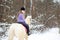 Young rider girl on albino horse in winter forest