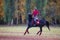 Young rider girl on bay horse in the autumn park