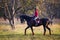 Young rider girl on bay horse in the park