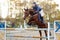 Young rider girl at show jumping. Jump hurdle