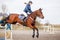 Young rider girl at show jumping. Jump hurdle