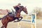 Young rider girl at show jumping. Jump hurdle