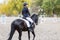 Young rider woman on horse on dressage competition