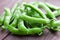 Young ripe and juicy pods of green peas on wooden background