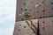 A young rock climber descends from an artificial mountain with safety cords and ropes in a sports amusement park