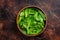 Young romain green salad leaves in wooden plate. Dark background. Top view