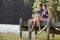 Young Romantic Couple Sitting On Wooden Jetty Looking Out Over Lake