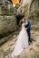 Young and romantic newlywed couple kissing in weathered rock cleft