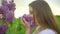 Young romantic smiling beautiful woman sniffing smelling lilac flowers in bouquet in nature outdoors