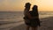 Young romantic travelers looking to the beach sky, enjoying sunset at the sea - love, summer and travel concept.