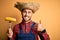 Young rural farmer man holding countryside corn over isolated yellow background happy with big smile doing ok sign, thumb up with