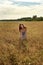 young rural girl in sarafan dress on a wheat field peacefully with delight leads hands touching spikelets