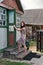 Young rustic teacher woman in retro dress with old-fashioned suitcase opens the door of a rural school holding the door handle