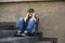 Young sad and desperate man sitting outdoors at street stairs suffering anxiety and depression feeling miserable crying in