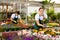 Young salesgirl arranging pots with blooming gazania in garden store