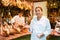 Young salesgirl in white uniform offering Iberian jamon in butcher shop