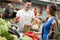 Young salesman smiling and holding vegetable at market